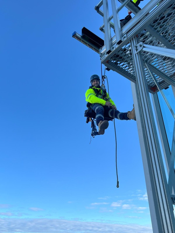 Rope access technician suspended against a large glass façade